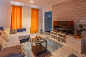 a living room with a couch and a flat screen tv at Sukorose Jacuzzis Vendégház in Sukoró