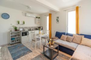 a living room with a blue couch and a kitchen at Sukorose Jacuzzis Vendégház in Sukoró