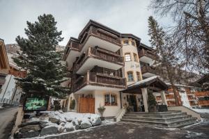 a large house with wooden balconies on a snowy street at La Perle Apartments in Zermatt