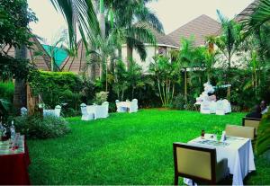 a garden with white tables and chairs on a lawn at Bustani Tulivu in Bungoma