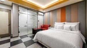 a bedroom with a white bed and a red chair at Hive Hotel in Tongduch'ŏn