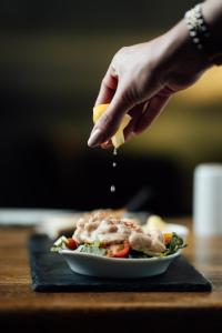 a person holding a slice of lemon next to a plate of food at St James Hotel in Grimsby