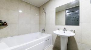 a white bathroom with a sink and a bath tub and a sink at Hive Hotel in Tongduch'ŏn +3 photos