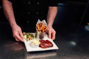 a man holding a plate of food with fries and dips at St James Hotel in Grimsby