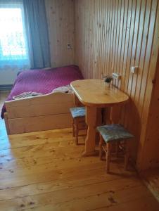 a room with a wooden table and a bed at Вершина спокою in Mykulychyn