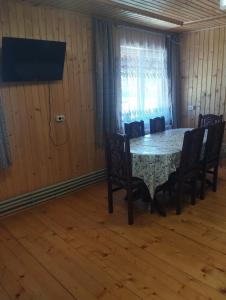a dining room with a table and chairs and a television at Вершина спокою in Mykulychyn