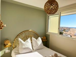 a bedroom with a bed with white pillows and a window at La Tour Alba in Valras-Plage