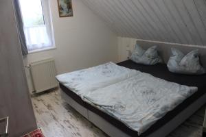 a bedroom with a bed with white sheets and pillows at Pension Danzer in Oberhof