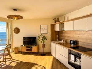 a kitchen with white cabinets and a view of the ocean at La Tour Alba in Valras-Plage