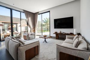 a living room with two chairs and a flat screen tv at The Reef Villa in Bahlāʼ
