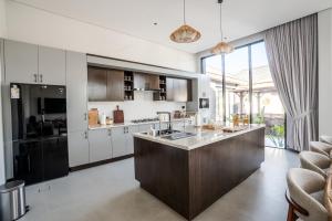 an open kitchen with white cabinets and a large window at The Reef Villa in Bahlāʼ