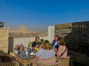 a group of people sitting at a table with the pyramid at Makan Pyramids Hotel in Cairo