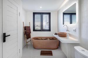 a bathroom with a large tub sitting next to a sink at Pyramid Ateliero Hotel Canggu in Canggu