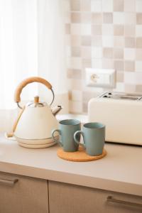 two coffee cups and a tea kettle on a kitchen counter at Zest House Pompei in Pompei