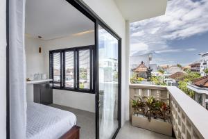 a bedroom with a balcony with a bed and a window at Pyramid Ateliero Hotel Canggu in Canggu