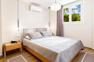 a white bedroom with a bed and a window at Poly's Villa Lefkada in Lefkada