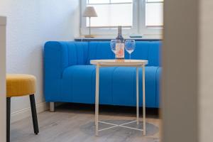 a table with two wine glasses on it next to a blue couch at Alte Dorfstraße 29 REETungsinsel in Behrensdorf
