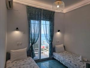 two beds in a room with a large window at Hotel Prinos in Skala Prinou