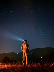a man standing in a field looking at the night sky at Tent-It India Experiences in Mukteshwar