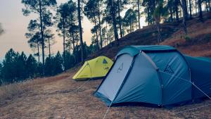 two tents on a hill with trees in the background at Tent-It India Experiences in Mukteshwar