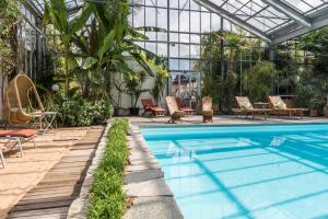 a swimming pool in a greenhouse with chairs and tables at B&B GoldRain in Coldrano