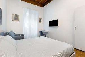 a white bedroom with a bed and a tv at Ser Lapo - Dimora storica a Prato in Prato