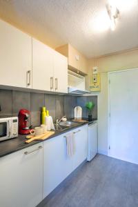 a kitchen with white cabinets and a microwave at L'Orée in Turckheim