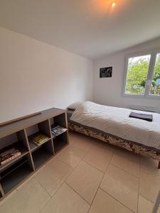 a bedroom with a bed and a table and a window at La Maison des Eléphants in Vivonne