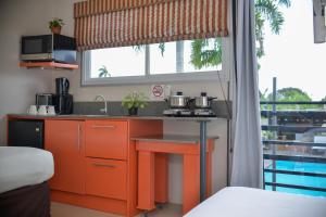 a kitchen with orange cabinets and a sink in front of a window at Elementz Apartments in Paramaribo