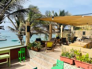 a patio with chairs and tables and the ocean at La Cabane du Pêcheur Atlantic Evasion in Dakar