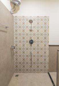 a bathroom with a shower with a tile wall at Nadhima Villas in Kumbakonam