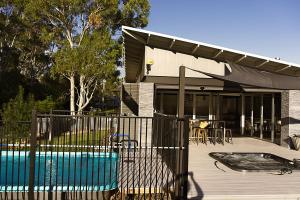 a house with a swimming pool and a deck with a fence at Jasmine Escape SPA Pool Secluded Bush Views in Ellalong