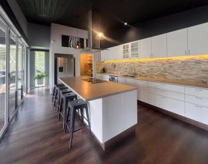 a kitchen with white cabinets and a island with bar stools at Jasmine Escape SPA Pool Secluded Bush Views in Ellalong
