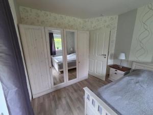 a bedroom with white walls and a bed with a mirror at Haus Küstenheide in Cuxhaven
