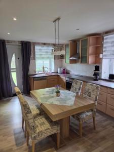 a kitchen with a wooden dining table and chairs at Haus Küstenheide in Cuxhaven +3 photos