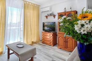 a living room with a tv and a vase of flowers at Azul. Cómodo, bonito y céntrico in Calpe