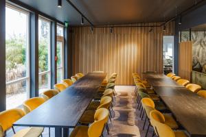 a row of tables and chairs in a room with windows at Hostel SLEPS in Augsburg