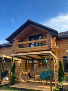 a cabin with a deck with chairs and a swing at Наше Місце in Krymno