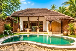 a swimming pool in front of a house at Amritara A Beach Symphony in Mararikulam