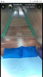 ein Bett mit blauen Kissen in einem Zimmer mit einer Holzwand in der Unterkunft Caveira in Mairiporã