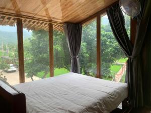 a bed in a room with a large window at Mai Chau Mountain Delight in Mai Châu