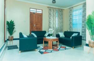 a living room with two blue couches and a table at Kamur Homes Apartment in Dodoma +3 photos