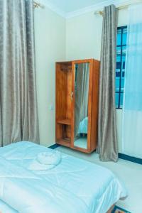 a bedroom with a bed and a cabinet with a mirror at Kamur Homes Apartment in Dodoma