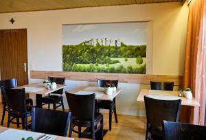 a restaurant with tables and chairs and a painting on the wall at Pension Schöpke in Bad Staffelstein