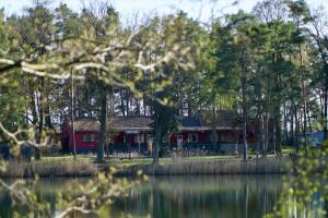 a red house next to a body of water at Schlaffass direkt am See in Heideblick