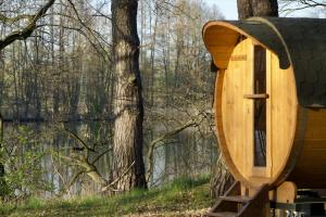 a wooden boat sitting next to a tree at Schlaffass direkt am See in Heideblick