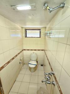 a small bathroom with a toilet and a window at Hotel Gazala in Palakkad