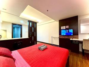 a bedroom with a red bed and a flat screen tv at EasyStay Studio Apartment KBCP in Kota Bharu