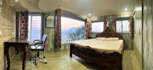 a bedroom with a bed and a desk and a window at Swami Manjulanand Ashram in Mohan Chatti