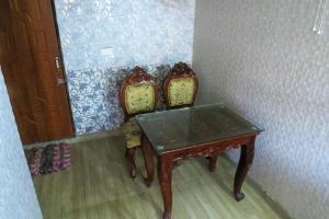 a wooden table and two chairs in a room at Swami Manjulanand Ashram in Mohan Chatti